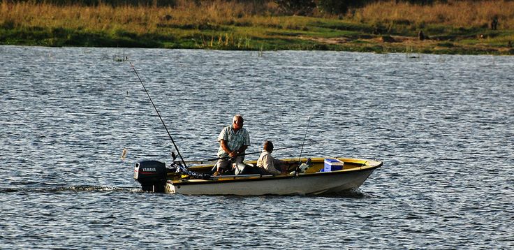 Tourists trolling for Nile Perch in a motorized fishing boat on the calm waters of Lake Victoria at sunset, an activity offered by Roadrave Tours and Travel.