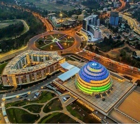 Stunning aerial shot of the Kigali Convention Centre illuminated in vibrant colors, showcasing modern architecture and city lights during a Rordrave Tours and Travel experience in Rwanda’s capital.