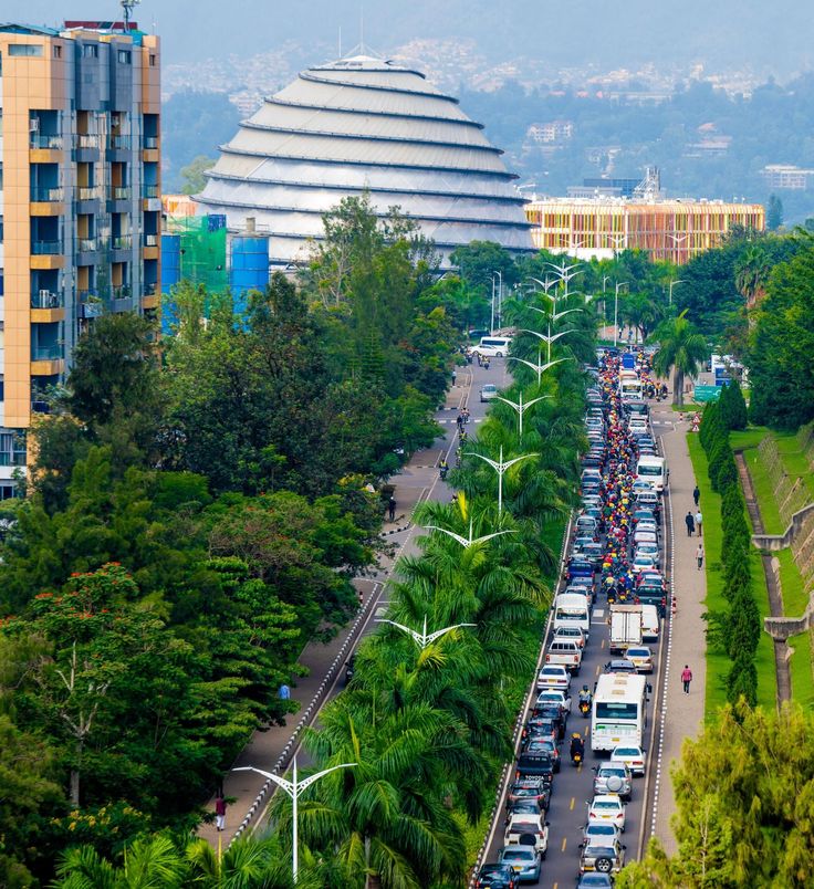 Busy street scene in Kigali with palm trees, modern buildings, and the iconic dome of the Kigali Convention Centre in the background, photographed during a Rordrave Tours and Travel city tour.