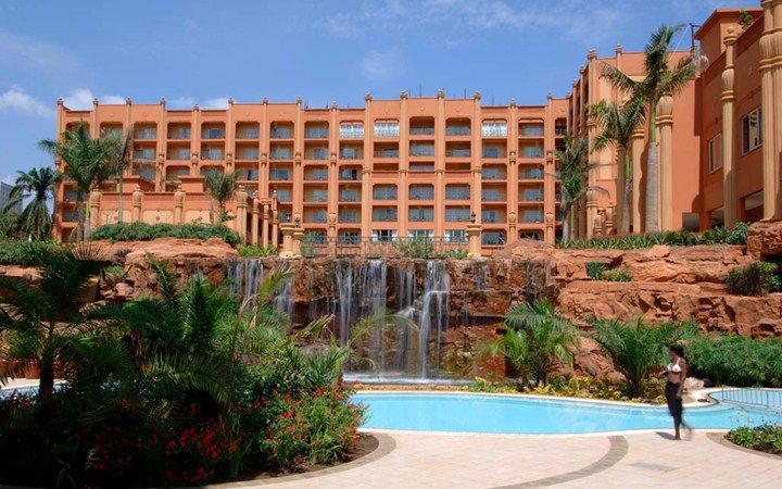 Kampala Serena Hotel exterior featuring luxury swimming pool and rock waterfall garden - Road Rave Tours