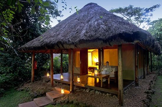 Luxury thatched safari tented cottage lit by lanterns at Sanctuary Gorilla Forest Camp in Bwindi Uganda - Road Rave Tours