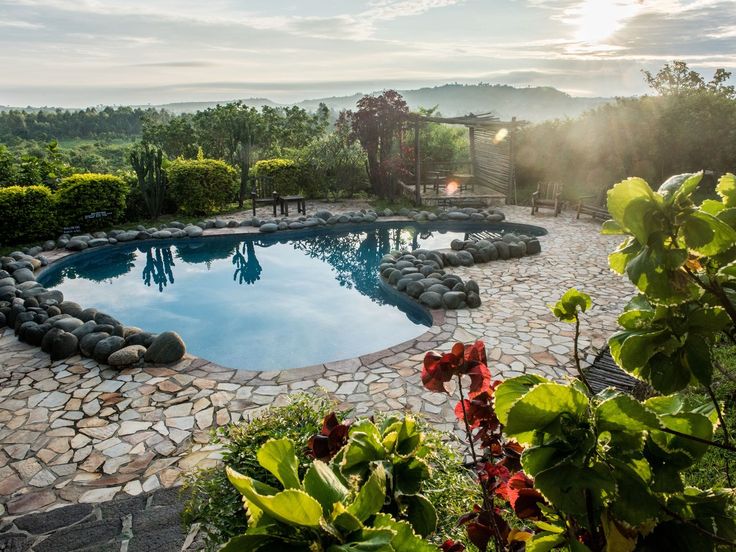 Outdoor stone swimming pool at Kyambura Gorge Lodge overlooking savanna landscape at sunrise - Road Rave Tours